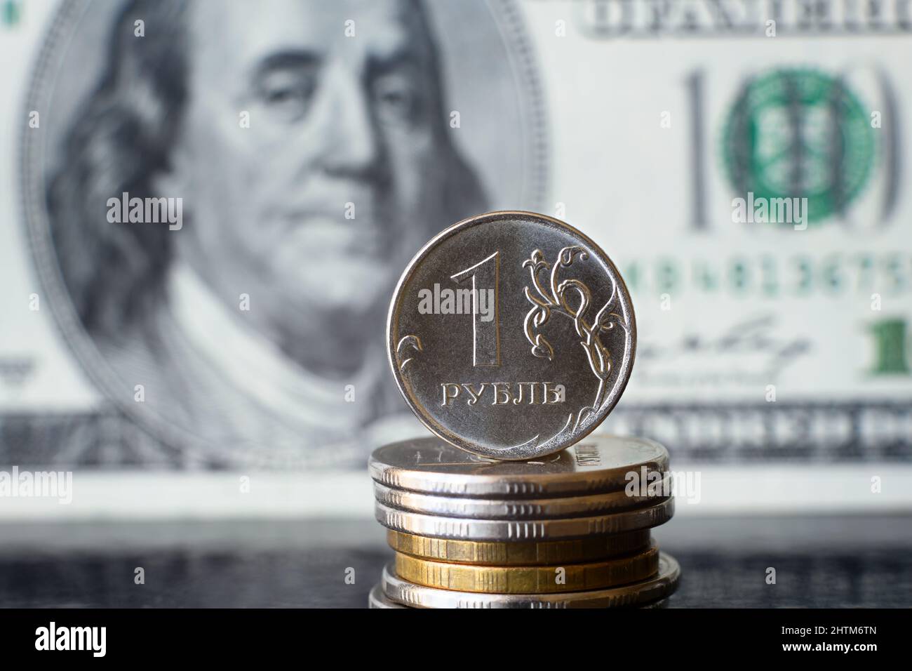 Russische Rubel-Münze vor dem Hintergrund der Dollarrechnung steht das Rubel-Geld unter dem Druck der Geopolitik. Konzept der Abwertung des Rubels, Inflation in Russland, eg Stockfoto
