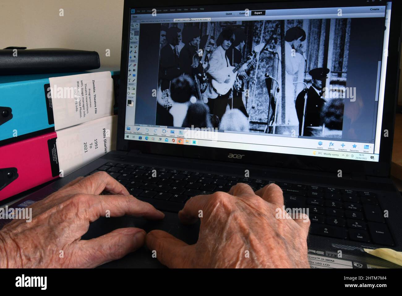 Alte Hände an einer Computertastatur, die Bilder finden, um angenehme Erinnerungen auszulösen, wenn man älter wird. Musik spielte eine wichtige Rolle im Leben in den 1960' Stockfoto