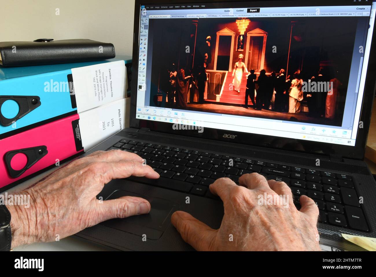 Alte Hände an einer Computertastatur finden Bilder, um angenehme Erinnerungen auszulösen, wie man älter wird.Diese Produktion des Musicals 'My Fair Lady' in der Stockfoto
