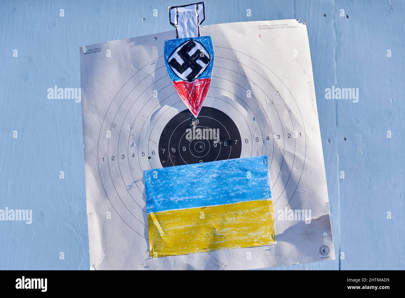 Helsinki, Finnland - 26. Februar 2022: Unterschreiben Sie mit einem Schießziel, einer Bombe und einem Hakenkreuz sowie einer ukrainischen Flagge bei einer Kundgebung gegen die militärische Aggression Russlands Stockfoto