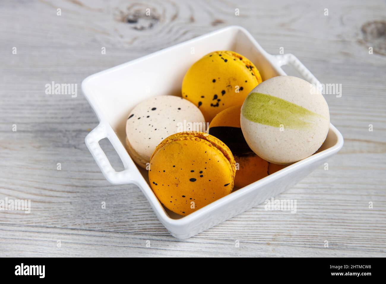 Gelbe und weiße Makronen in einer weißen Porzellanschale Stockfoto