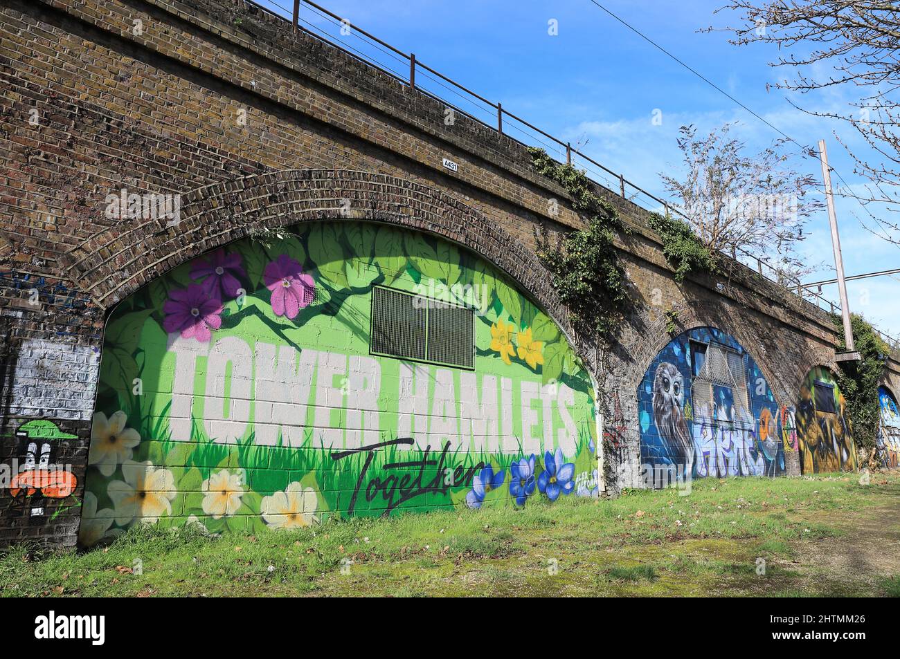 Ackroyd Drive Green Link, mit einem Wandgemälde von Alex Altona auf den Eisenbahnbögen und einem Teil des Tower Hamlets Cemetery Park in London, Großbritannien Stockfoto