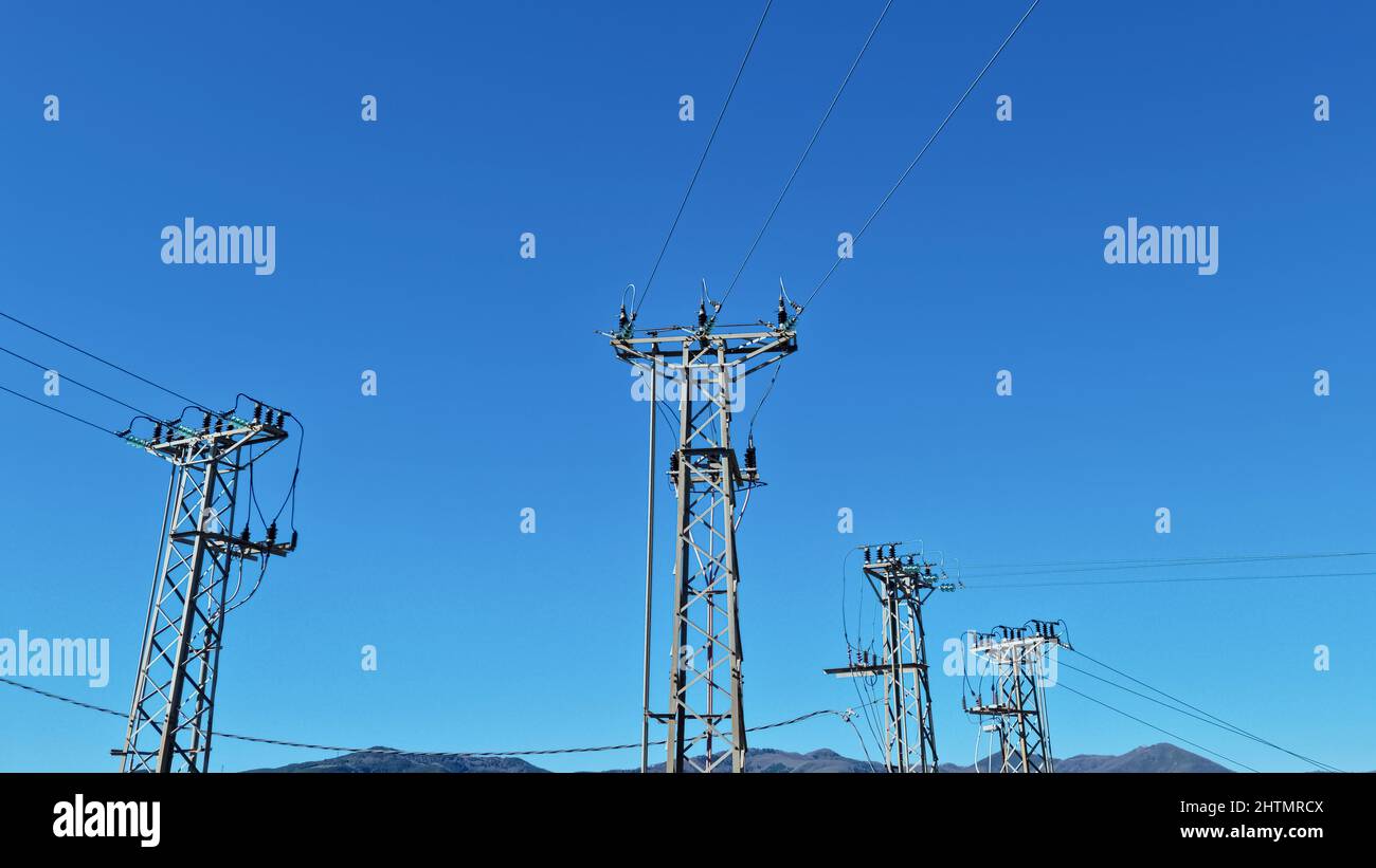 Hochspannungsmasten über dem klaren blauen Himmel, elektrische Energieinfrastruktur Stockfoto