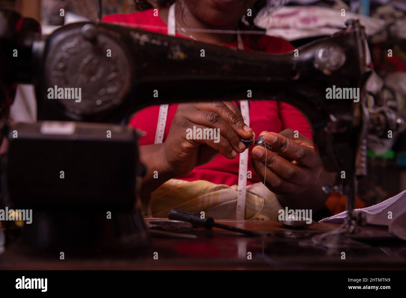 Nahaufnahme der Hände einer arbeitenden Näherin. Afrikanische Schneiderin in ihrem Schneiderladen Stockfoto