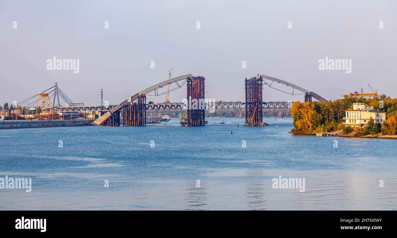 Die Podilskyi-Brücke, eine Straßen- und Eisenbahnbrücke, die den Dnjepr-Fluss von Podil bis zu den Woskresenka-Bezirken, Kiew (Kiew), Ukraine, überspannt, befindet sich im Bau Stockfoto