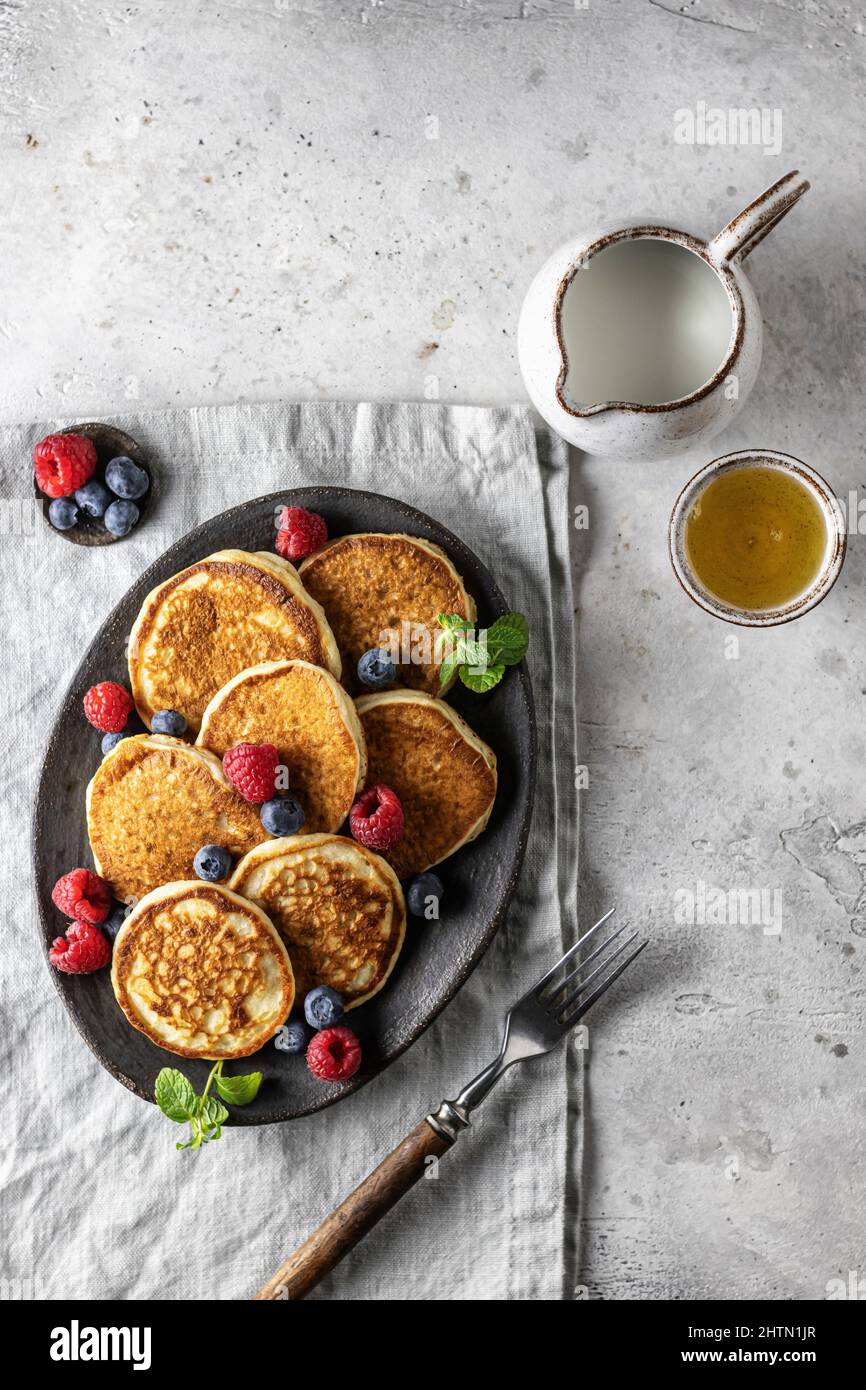 Pfannkuchen in Keramikplatte mit Beeren, Minzblättern, Soße Boote und Gabel auf Serviette, Draufsicht Stockfoto