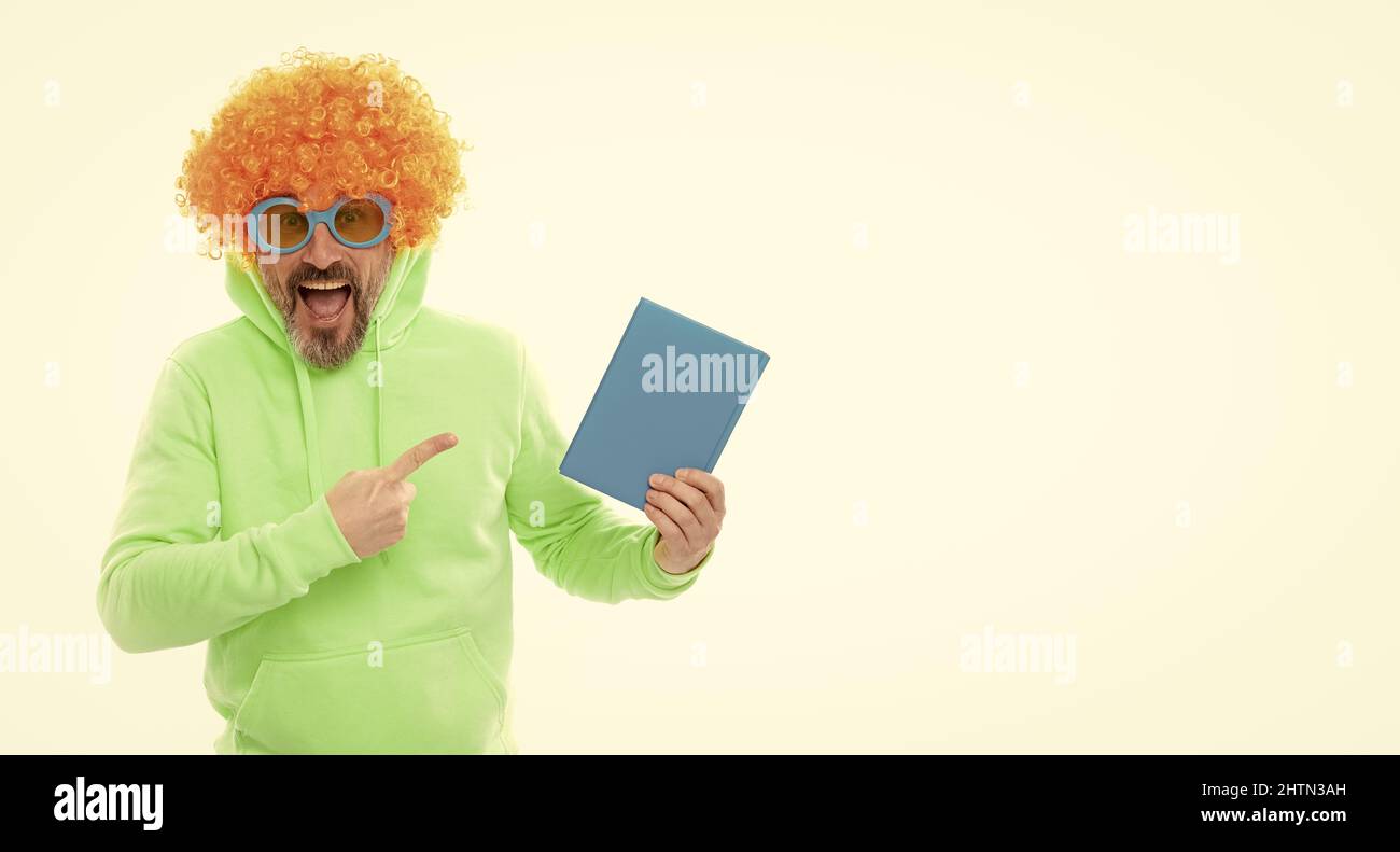 Verrückte Schullehrerin in Perücke und Sonnenbrille zeigen auf blauen Buchdeckel für Kopieplatz, Schulbuch Stockfoto