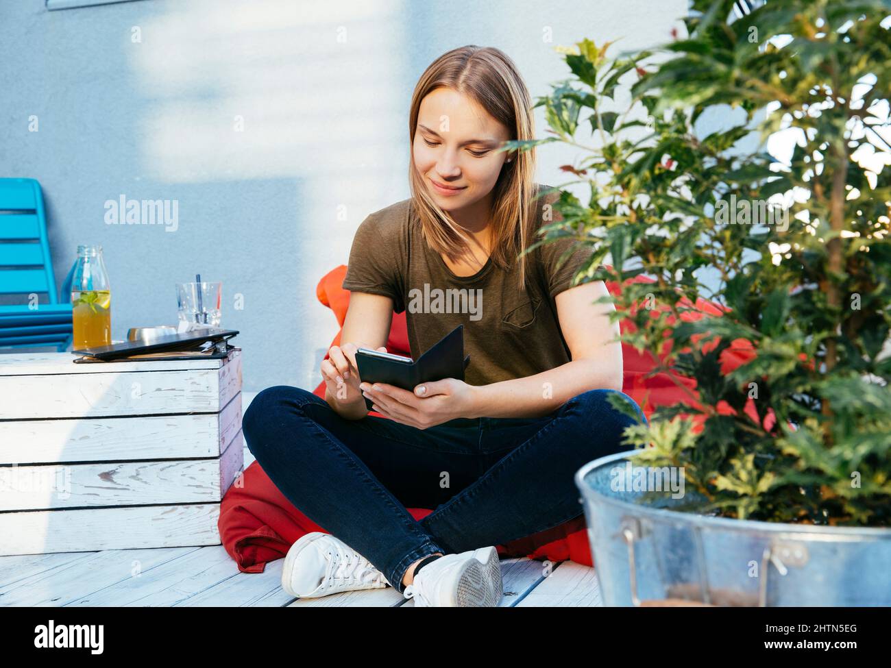 Junge Frau, die auf der Terrasse sitzt und telefoniert Stockfoto