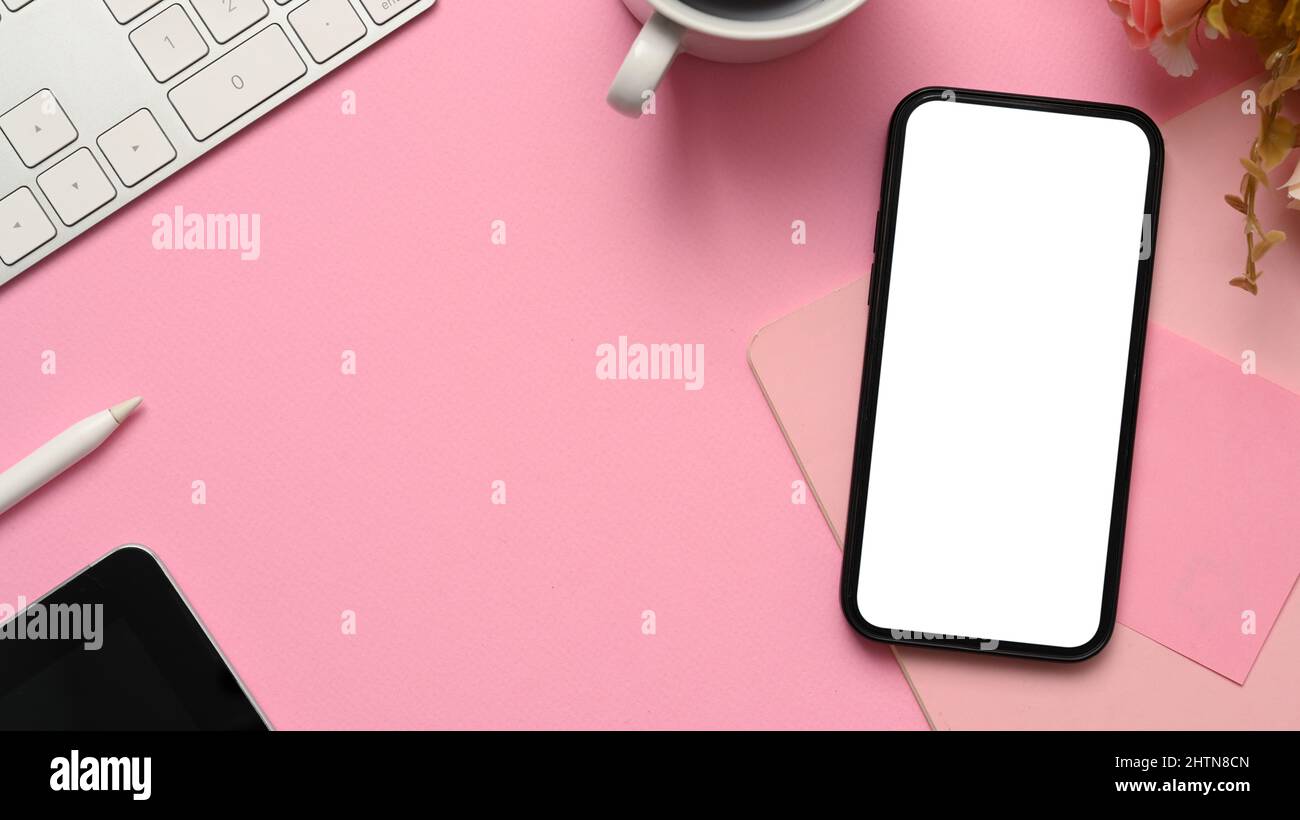 Overhead Shot, Pink Workspace Background mit Smartphone leerem Bildschirm Mockup, Tastatur, Kaffeetasse, Blume und Kopierraum. Stockfoto