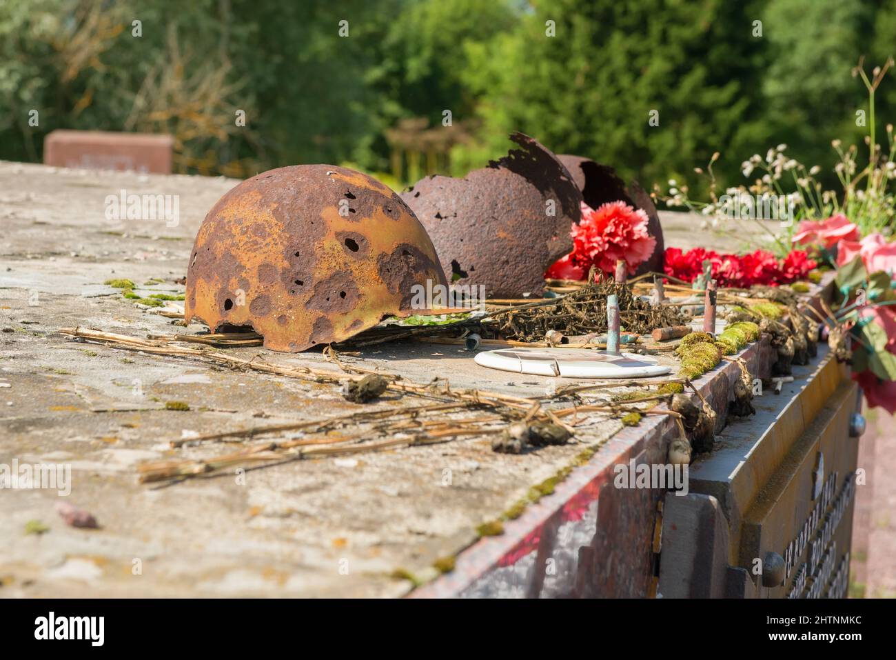 Alte, rostige und durchbrochene Soldatenhelme, die mit Blumen geschmückt sind Stockfoto