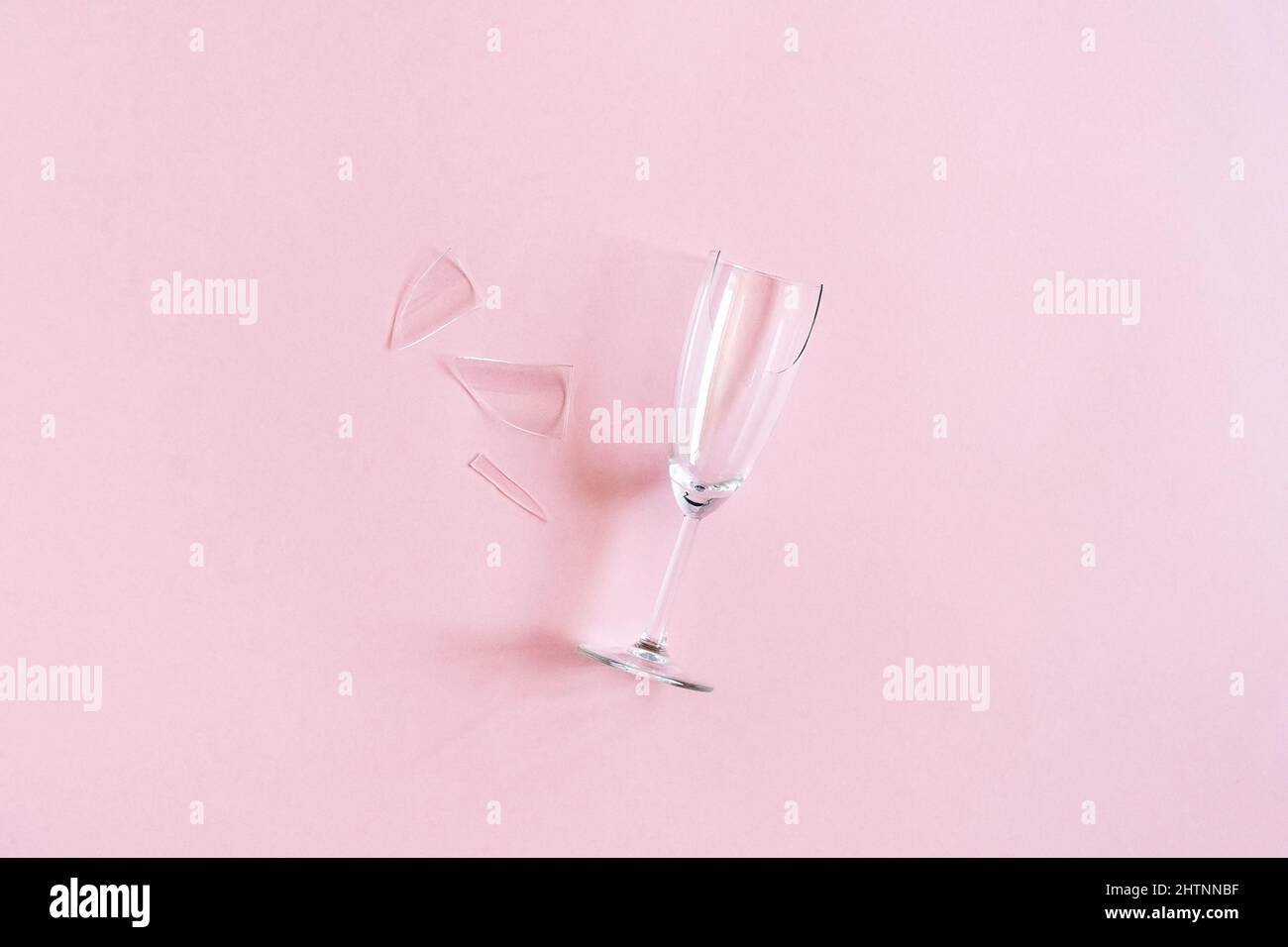 Gebrochene Sektflöte mit Splittern auf rosa Hintergrund mit Kopierraum. Konzept Kampf gegen Alkoholismus, Trunkenheit und Alkoholverweigerung. Kreati Stockfoto