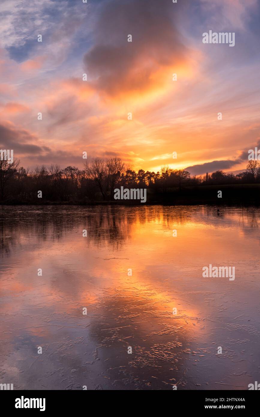 Farbenprächtiger Sonnenuntergang über einem gefrorenen See. Bulwell Hall Park Nottingham England Großbritannien Stockfoto