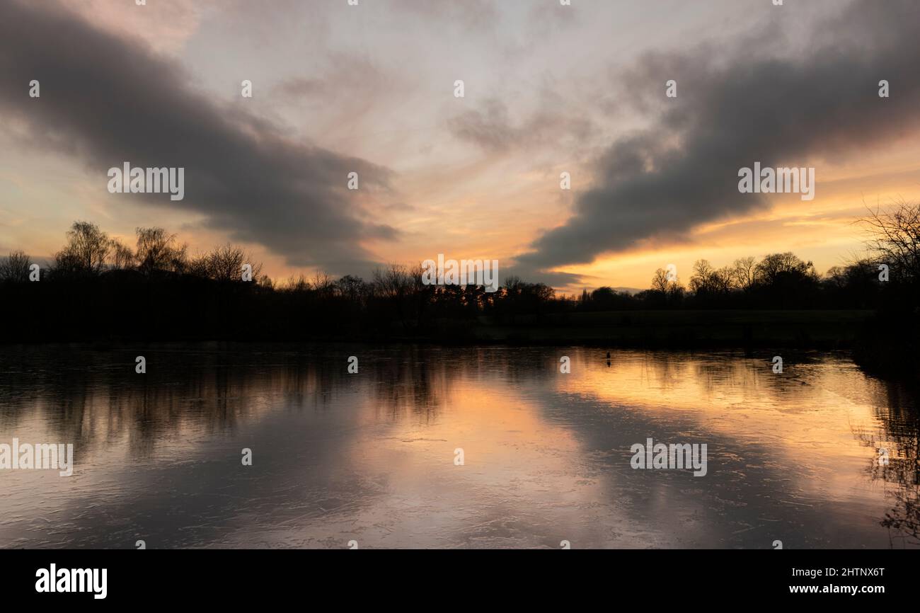 Farbenprächtiger Sonnenuntergang über einem gefrorenen See. Bulwell Hall Park Nottingham England Großbritannien Stockfoto