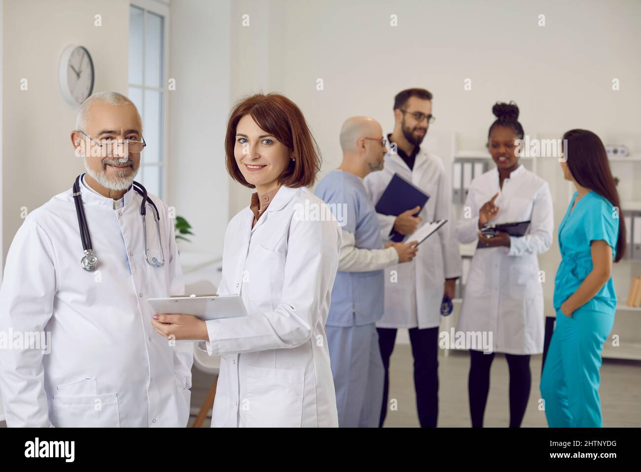 Porträt von zwei glücklichen, lächelnden Ärzten in weißen Mänteln bei der Arbeit in Klinik oder Krankenhaus Stockfoto