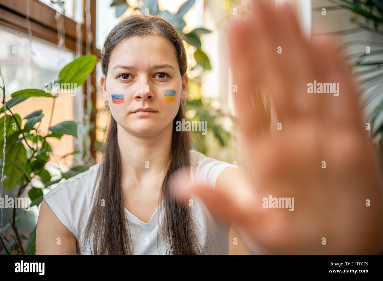 Ein junges russisch-ukrainisches Mädchen mit der Flagge der Ukraine und Russlands im Gesicht sagt Stop. Das Konzept der Beteiligung des ukrainischen Volkes an Stockfoto