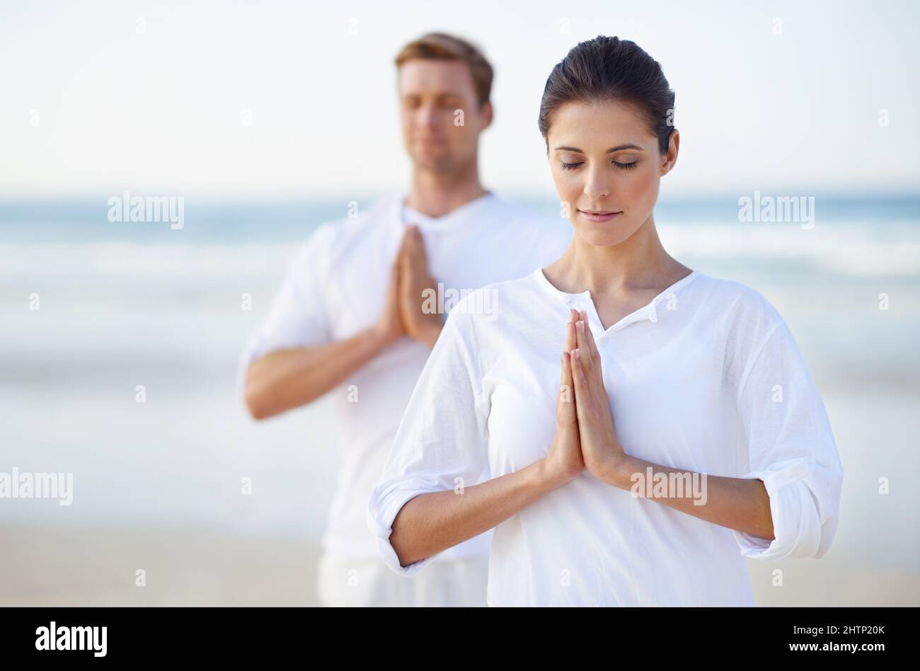 Yoga am Meer. Ein junges Paar, das am Strand Yoga praktiziert. Stockfoto
