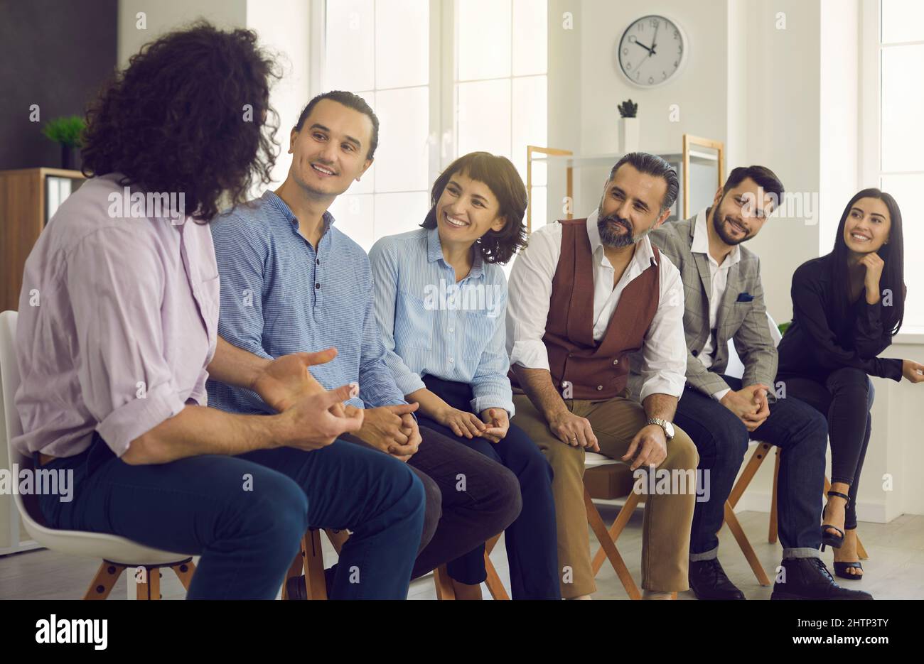 Gruppe von glücklichen interessierten Geschäftsleuten, die einem Kollegen während eines Meetings zuhören Stockfoto