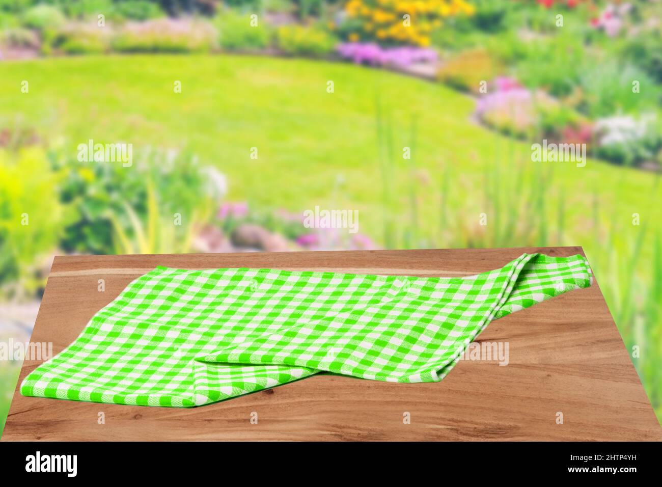 Leeres Tischprodukt. Leerer Holzdecktisch mit einer grün weiß karierten Tischdecke über abstrakt verschwommener natürlicher Kulisse. Platz für Ihre Fotolia Stockfoto