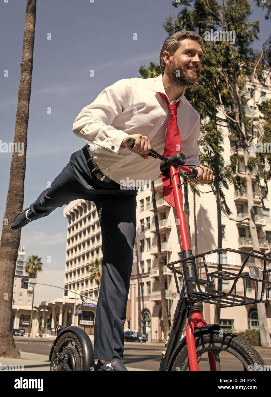 Glücklicher Chef in formalwear Fahrt City Scooter entlang Bürgersteig, scooting Stockfoto