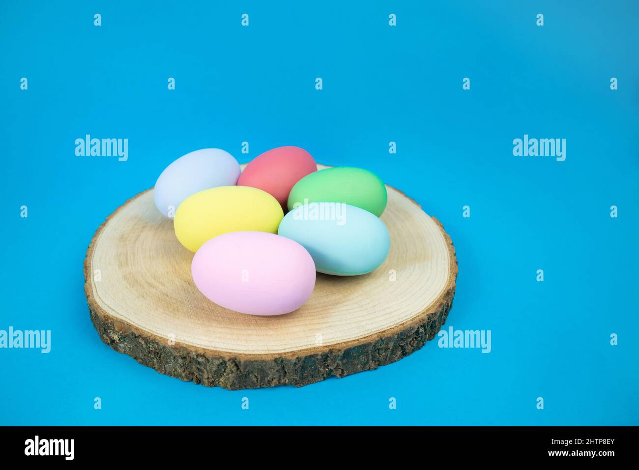 Ostereier, einfarbige, bunte Eier auf einem Hanfteller auf blauem Hintergrund Stockfoto