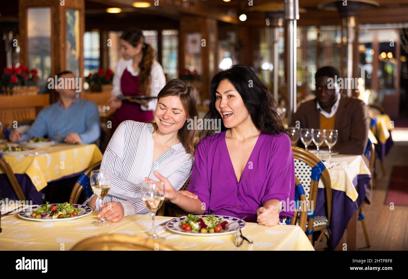 Treffen von zwei glücklichen Freundinnen beim Abendessen im Restaurant Stockfoto