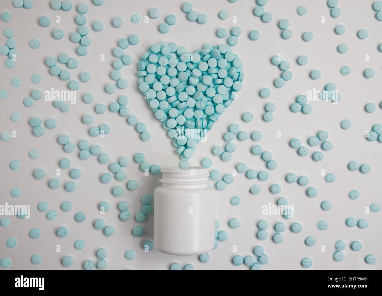 Ein Herz aus blauen Pillen und einem weißen Glas. Gesundheit, Medizin Stockfoto