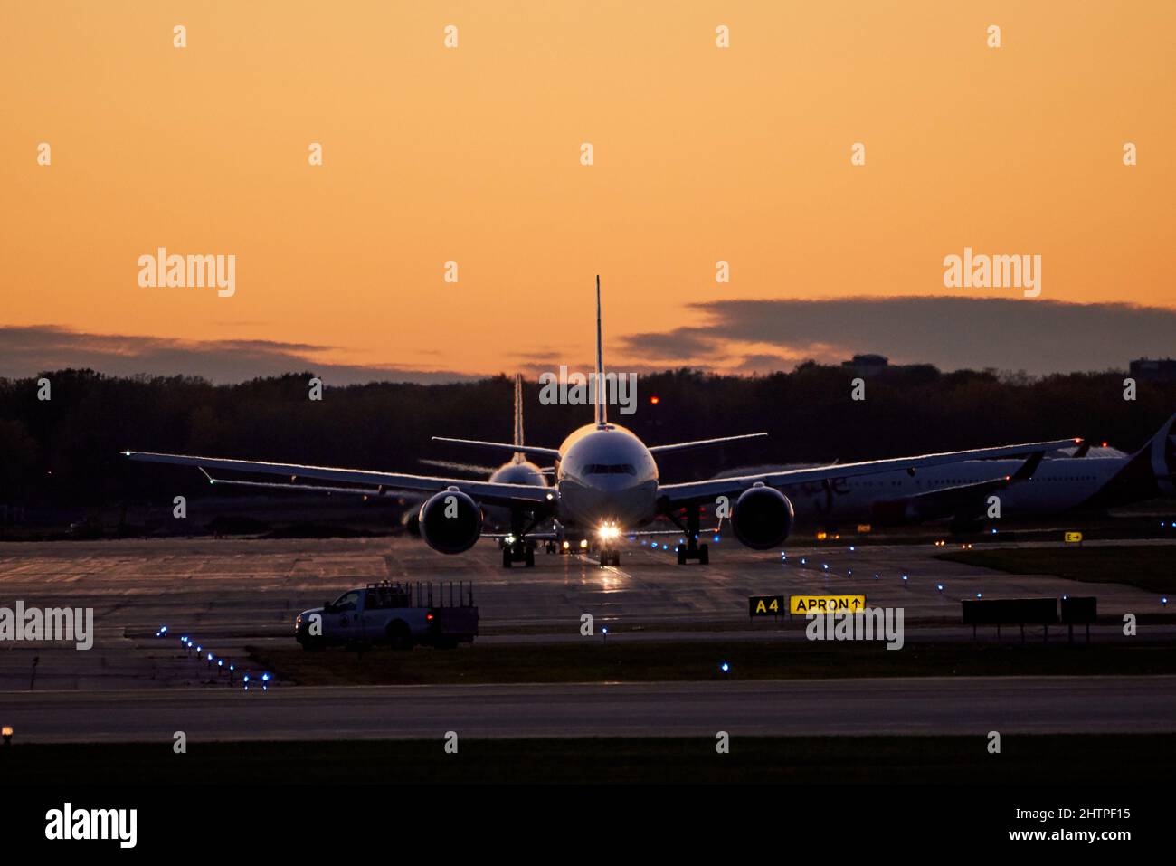 Fernansicht des Flugzeuges, das während des Sonnenuntergangs am Vorfeld des Flughafens geparkt wurde Stockfoto