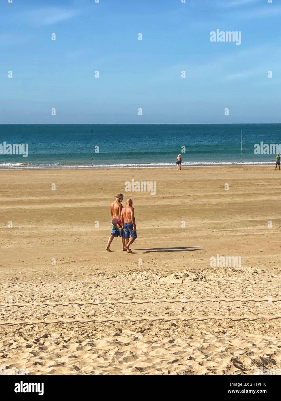 Zwei Männer, die gemeinsam an einem Strand in Andalusien spazieren Stockfoto