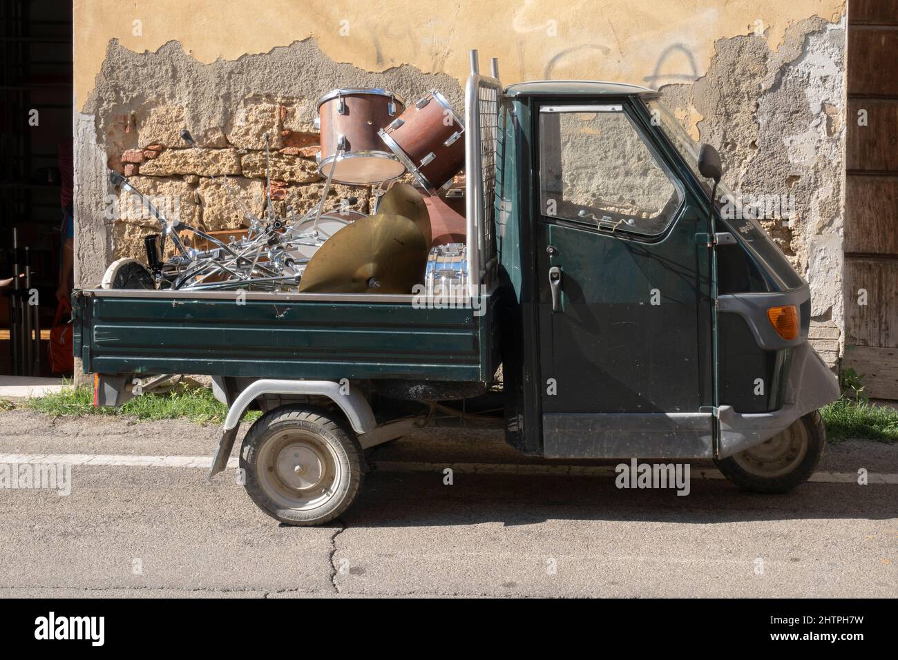 Transport von Musikinstrumenten durch das charakteristische Ape Piaggio, Asciano Dorf, Crete Senesi Gebiet, Provinz Siena, Toskana, Europa Stockfoto