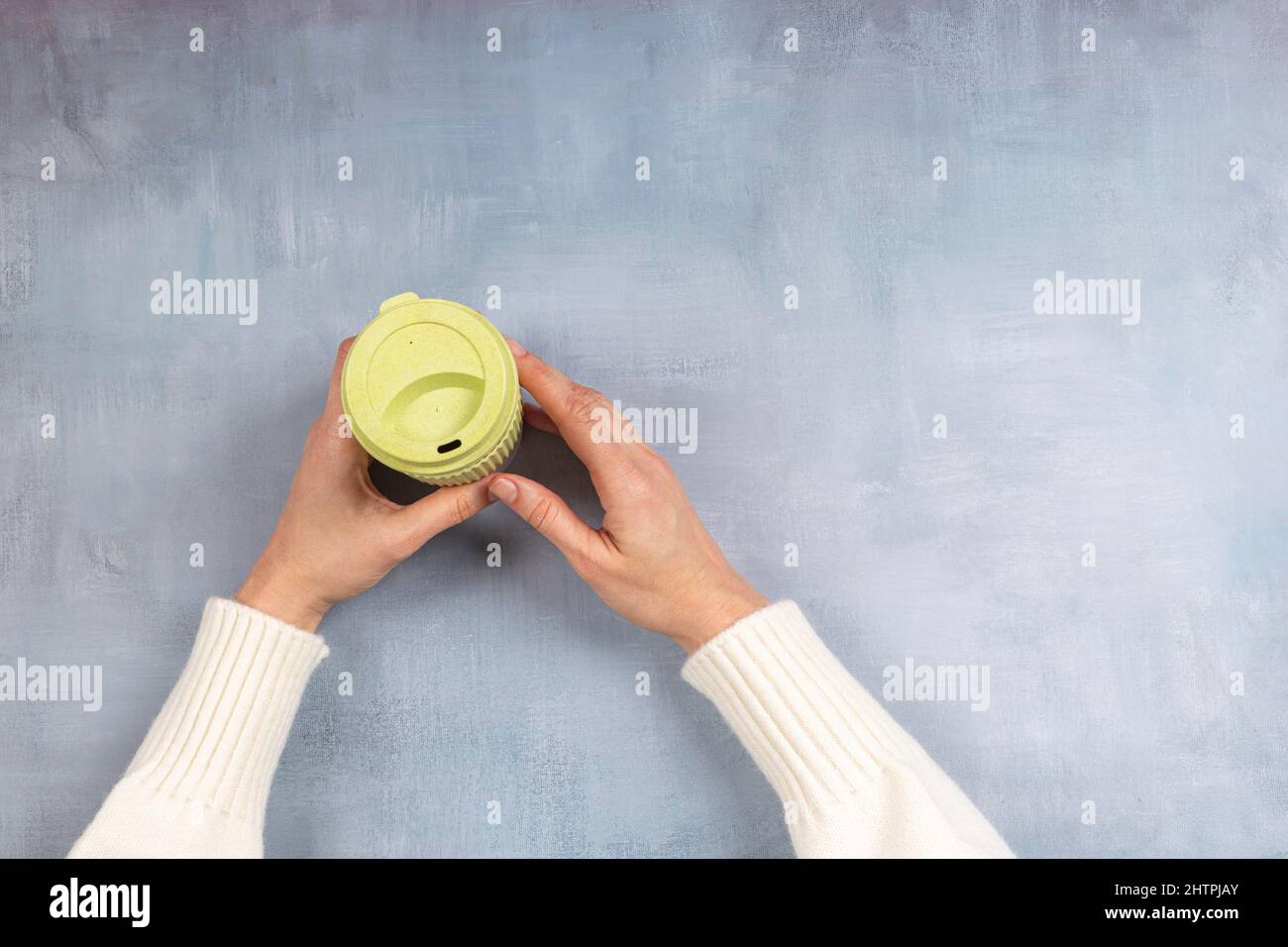 Nachhaltiges Wohnen, keine Verschwendung, kein Kunststoffkonzept. Weibliche Hand hält stilvolle wiederverwendbare umweltfreundliche Kaffeetasse auf grauem Hintergrund Stockfoto