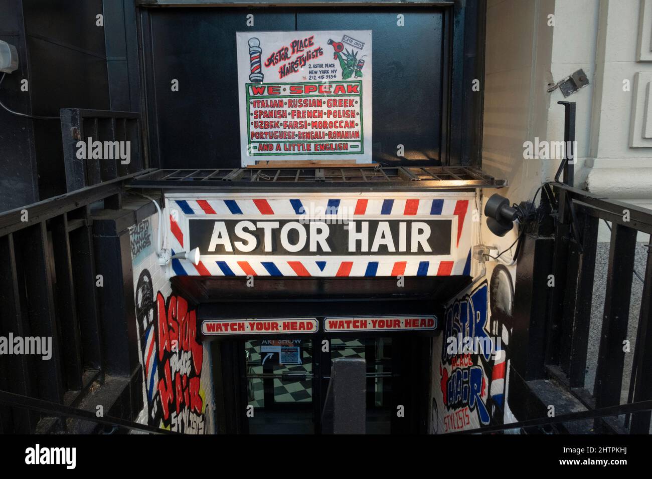 Ein Zeichen des Weges nach unten zu den Astor Hair Stylisten im East Village, Manhattan, New York City. Sie behaupten, dass dort 13 Sprachen gesprochen werden. Stockfoto