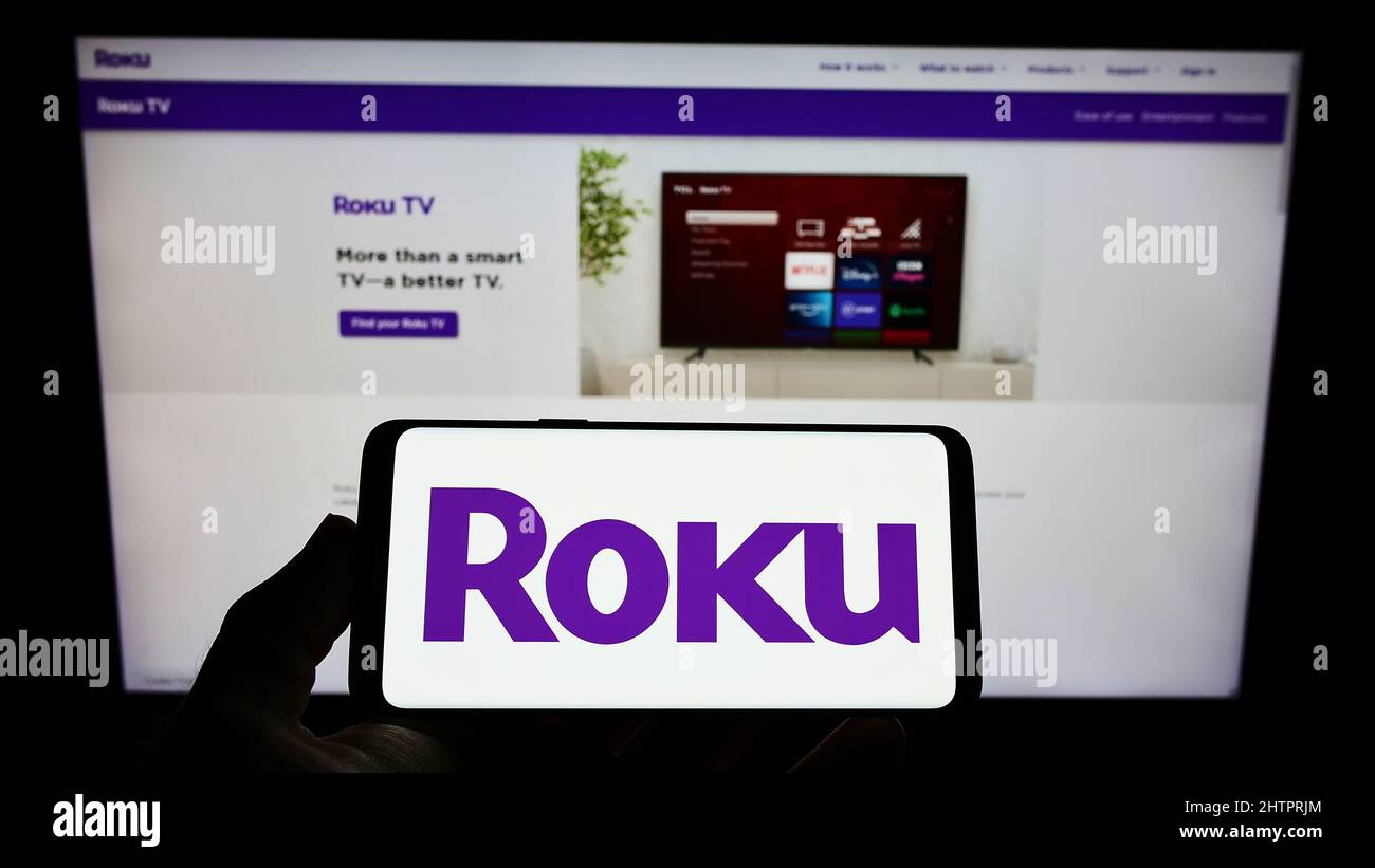 Person, die das Smartphone mit dem Logo des US-amerikanischen Video-Streaming-Unternehmens Roku Inc. Auf dem Bildschirm vor der Website hält. Konzentrieren Sie sich auf die Telefonanzeige. Stockfoto