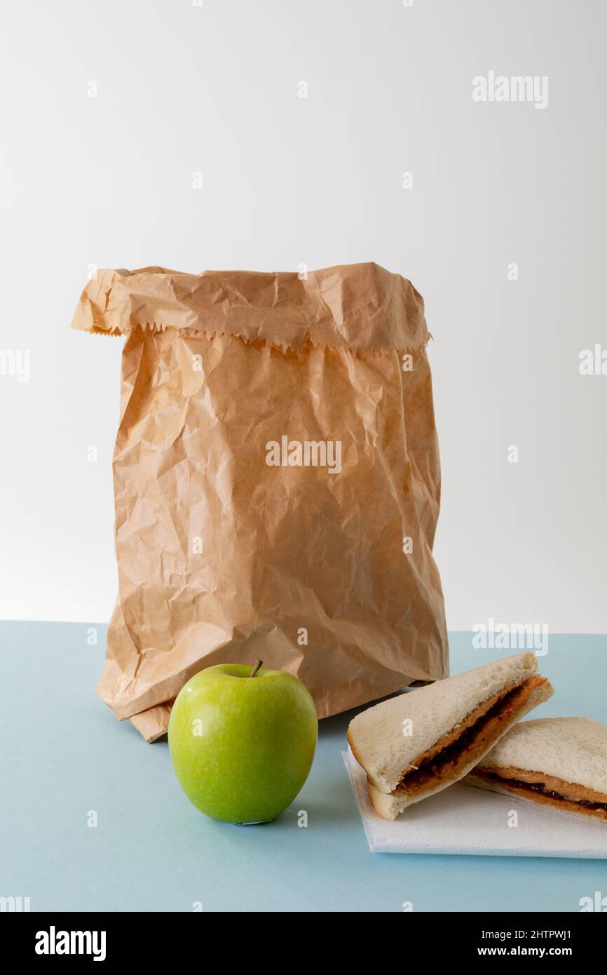 Grüner Apfel mit Papiertüte und Erdnussbutter und Gelee-Sandwich auf dem Tisch vor grauem Hintergrund Stockfoto