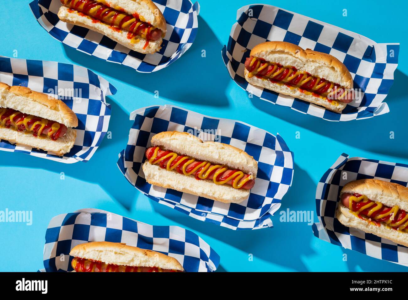 Hochwinkelansicht von Hot Dogs in Containern auf blauem Hintergrund angeordnet Stockfoto