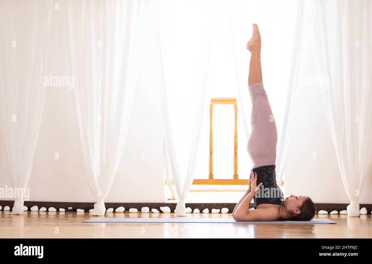 Junge Frau, die Sarvangasana oder Schulterstand Pose macht. Stockfoto