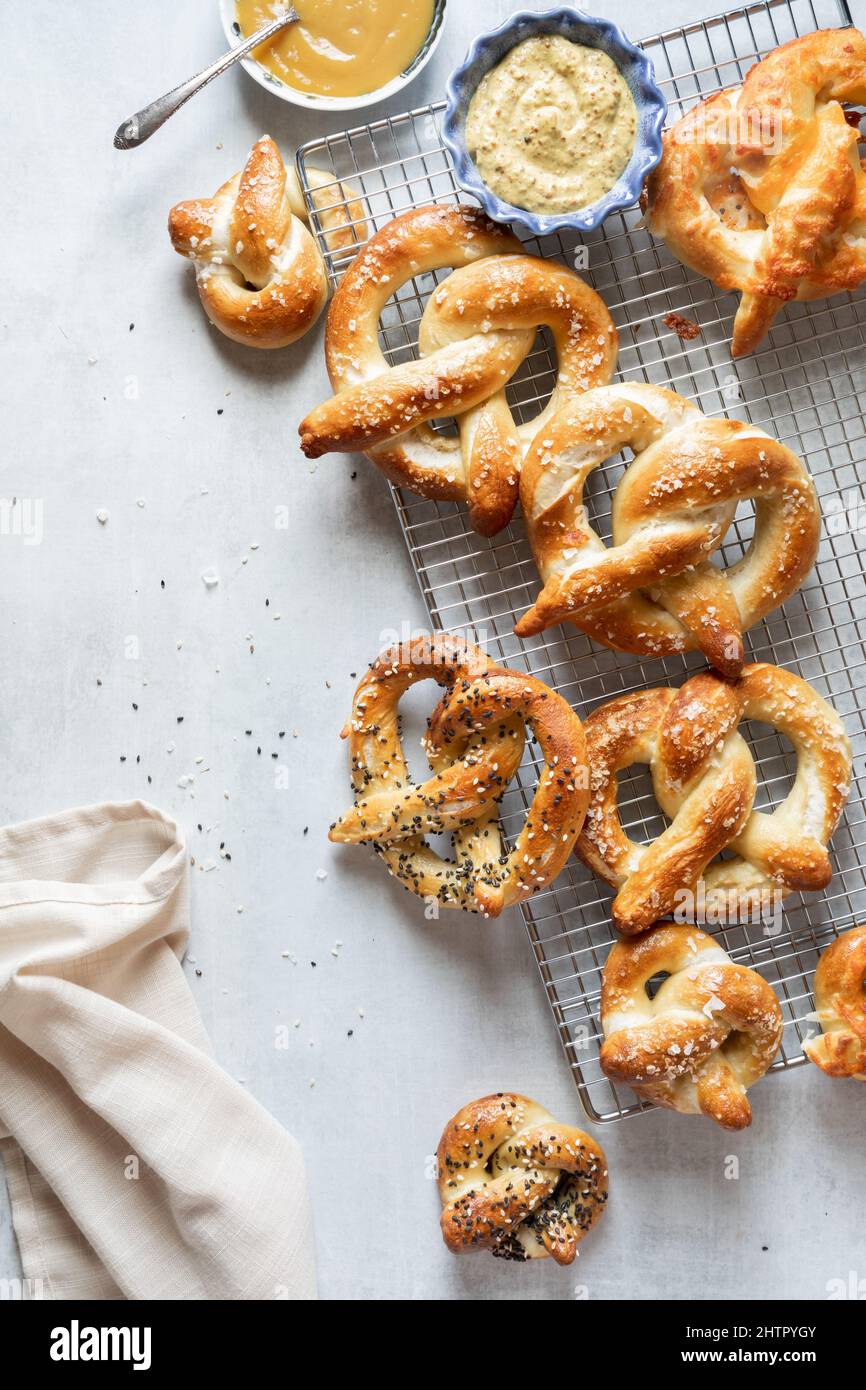 Frisch gebackene Brezeln auf einem Kühlregal, serviert mit Senfdips. Stockfoto