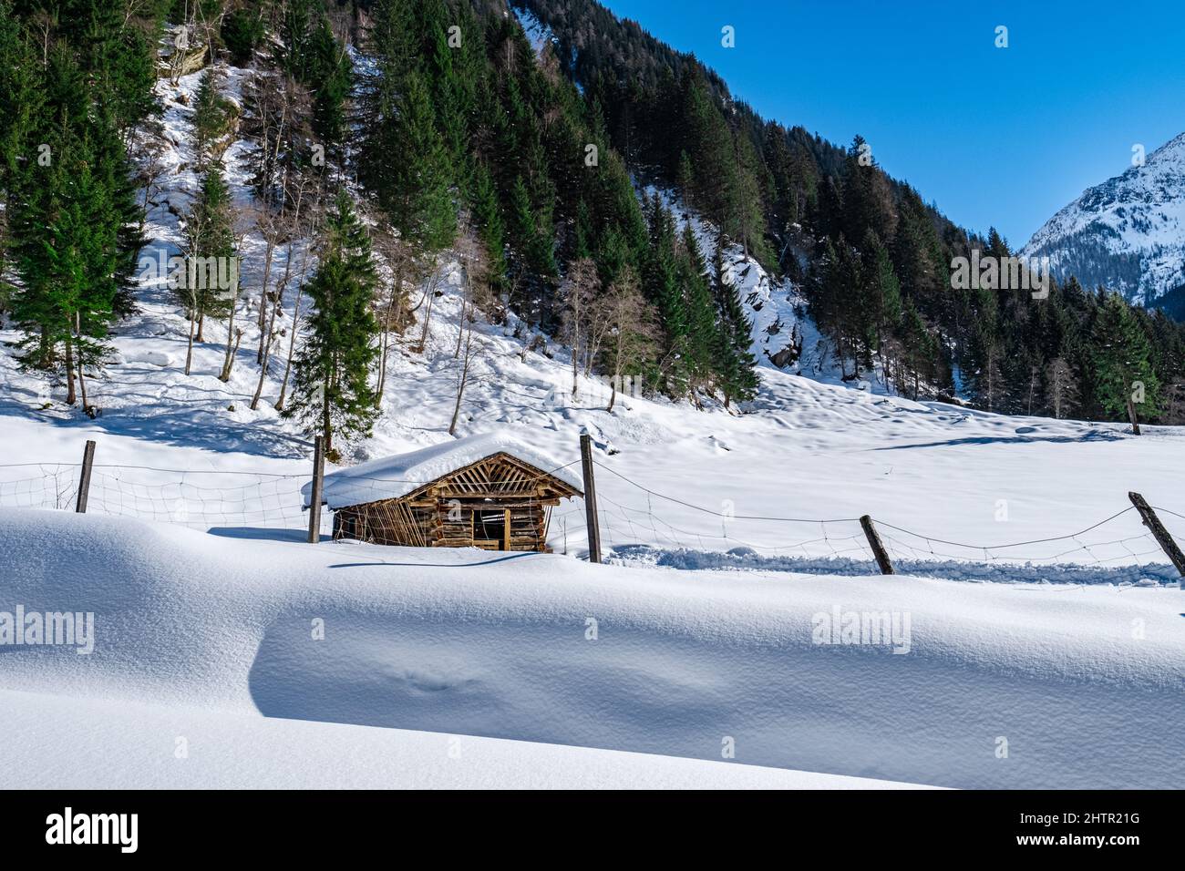 Holzhütte auf einem tief unberührten schneebedeckten Feld in einer Winterlandschaft mit blauem Himmel im Skigebiet Großarlberg Salzburg Österreich. Stockfoto