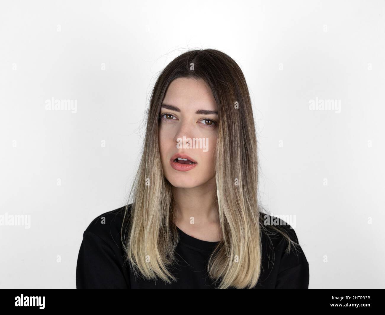 Junges Mädchen mit ernstem Gesichtsausdruck. Sie ist in Wut. Sie fragte etwas und sie wartet auf die Antwort. Weißer Studiohintergrund. Stockfoto