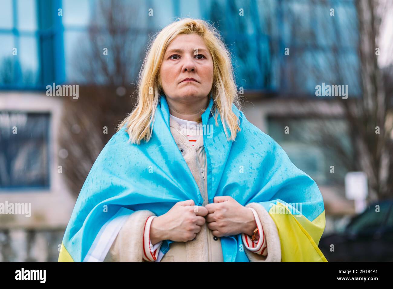 Ukrainische Frau mit blonden Haaren und einer ernsten Geste, mit einer blau-gelben ukrainischen Flagge, auf der Straße, um gegen den Ukraine-Russland-Krieg zu protestieren. Stockfoto
