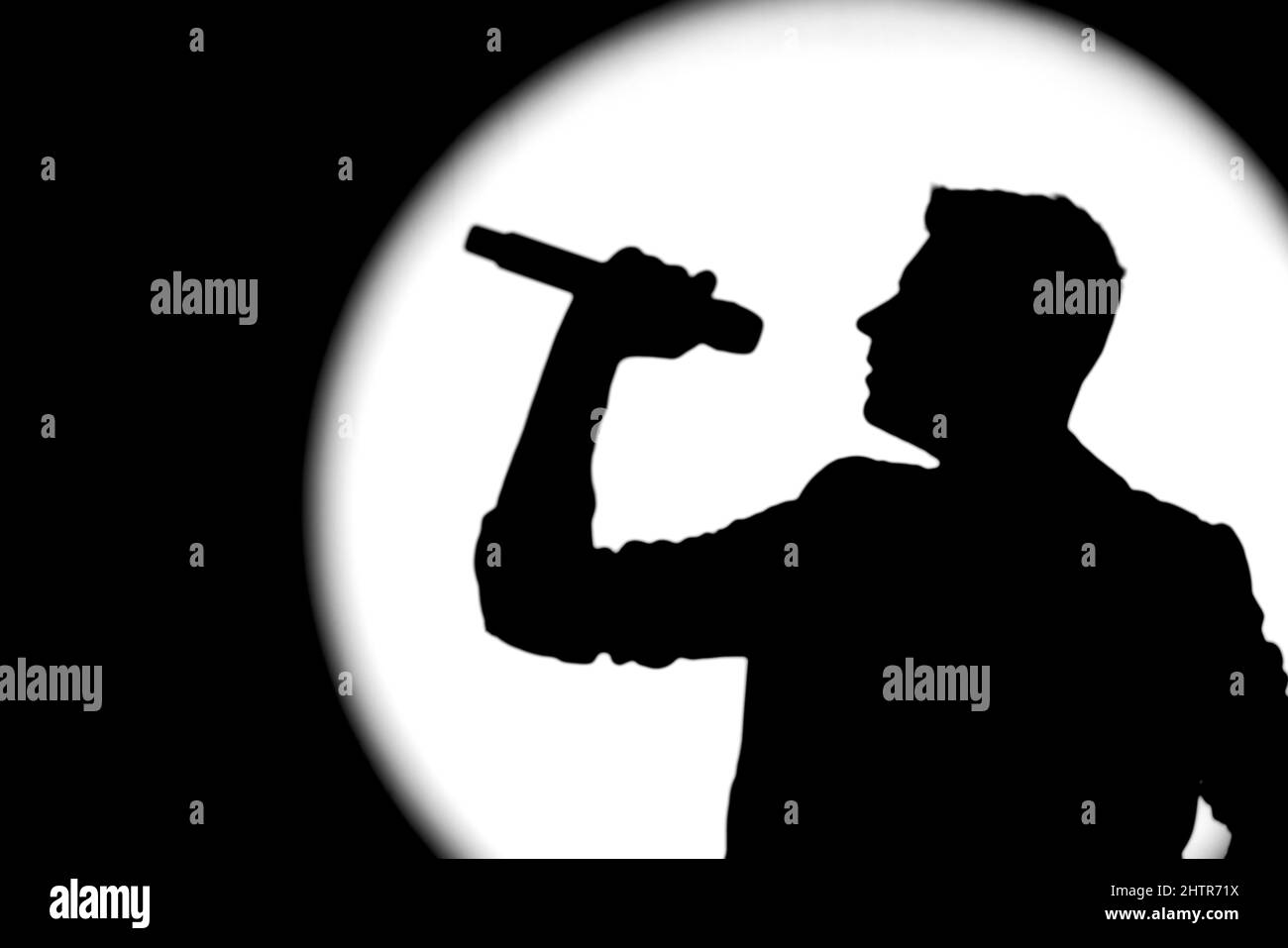 Silhouette eines männlichen Sängers, der mit Mikrofon singt Stockfoto