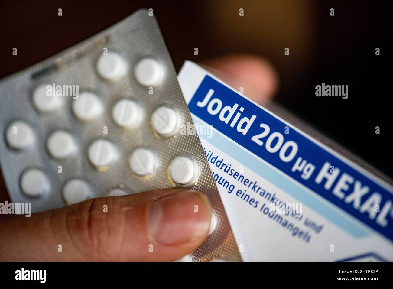 ILLUSTRATION - 02. März 2022, Berlin: Eine Person hält eine Packung  Jodid-Tabletten. Nach Angaben des Bundesamtes für Strahlenschutz kann  radioaktives Jod im Falle eines nuklearen Unfalls freigesetzt werden. Um  eine Anhäufung in