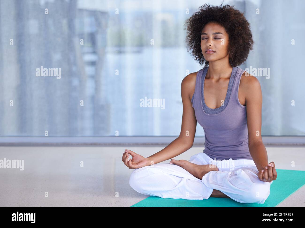 Innere Ruhe finden. Aufnahme einer attraktiven jungen Frau, die auf einer Übungsmatte meditiert. Stockfoto
