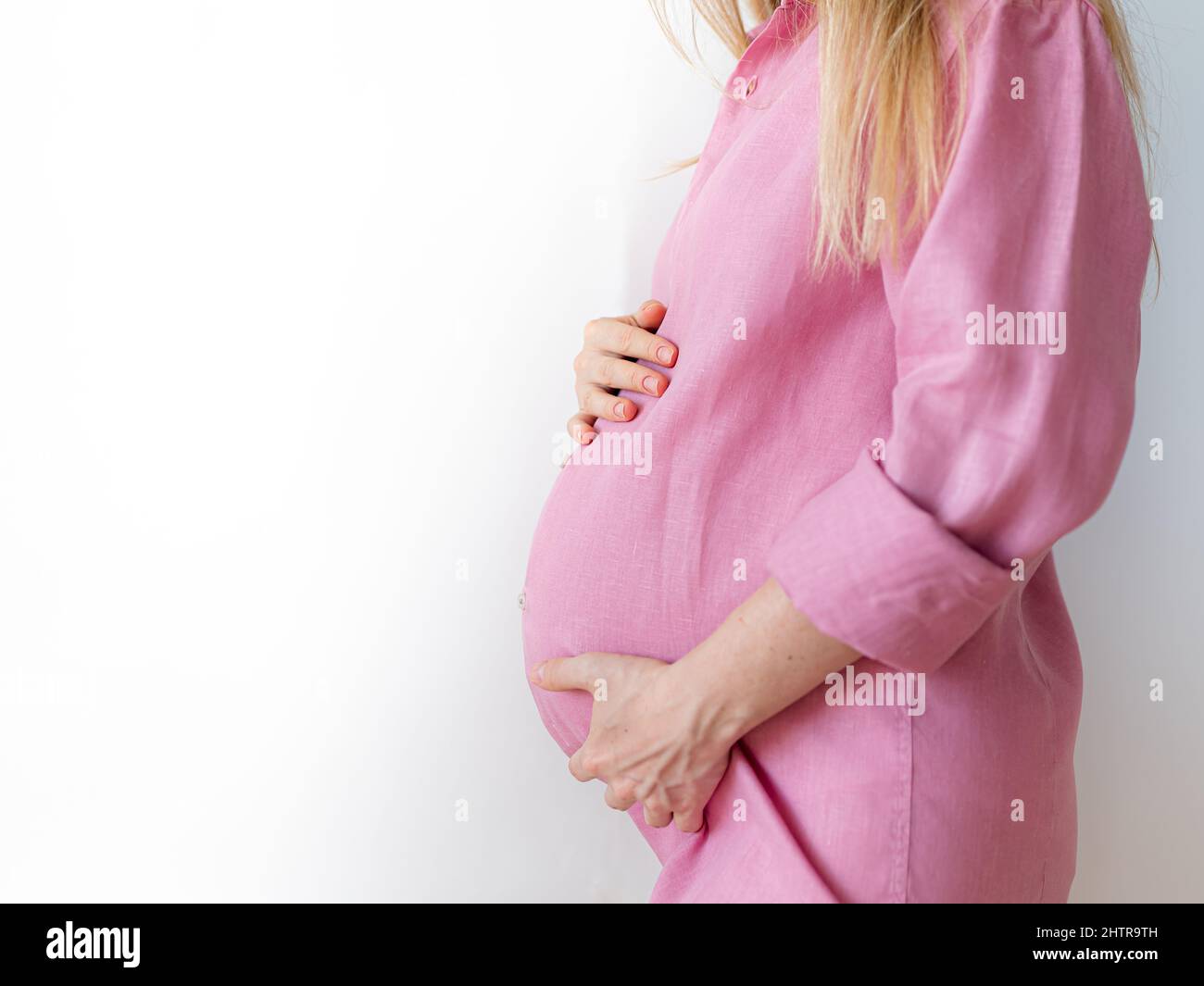 Eine Schwangere steht mit den Händen auf dem Bauch, das Konzept, ein Baby zu erwarten Stockfoto