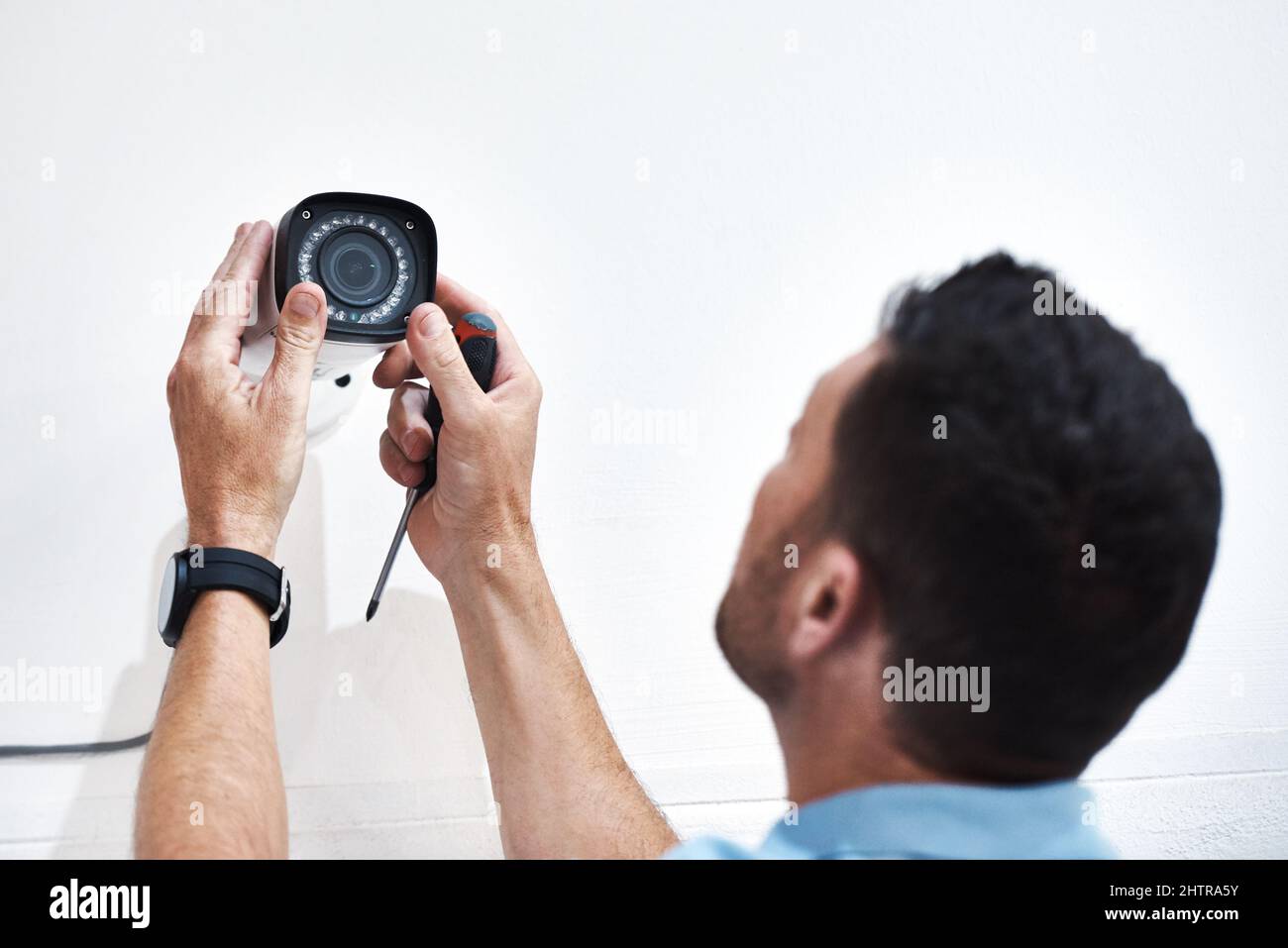 Könnt ihr mich da unten sehen? Aufnahme eines reifen Mannes, der eine Sicherheitskamera auf einem Gebäude installiert. Stockfoto