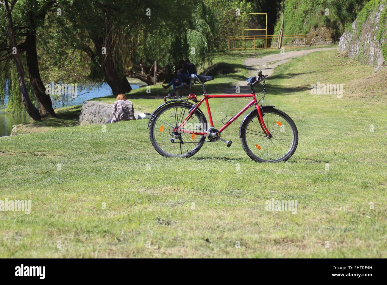 Rotes Fahrrad auf dem Gras am Ufer des Flusses Vrbas in Banja Luka Stockfoto