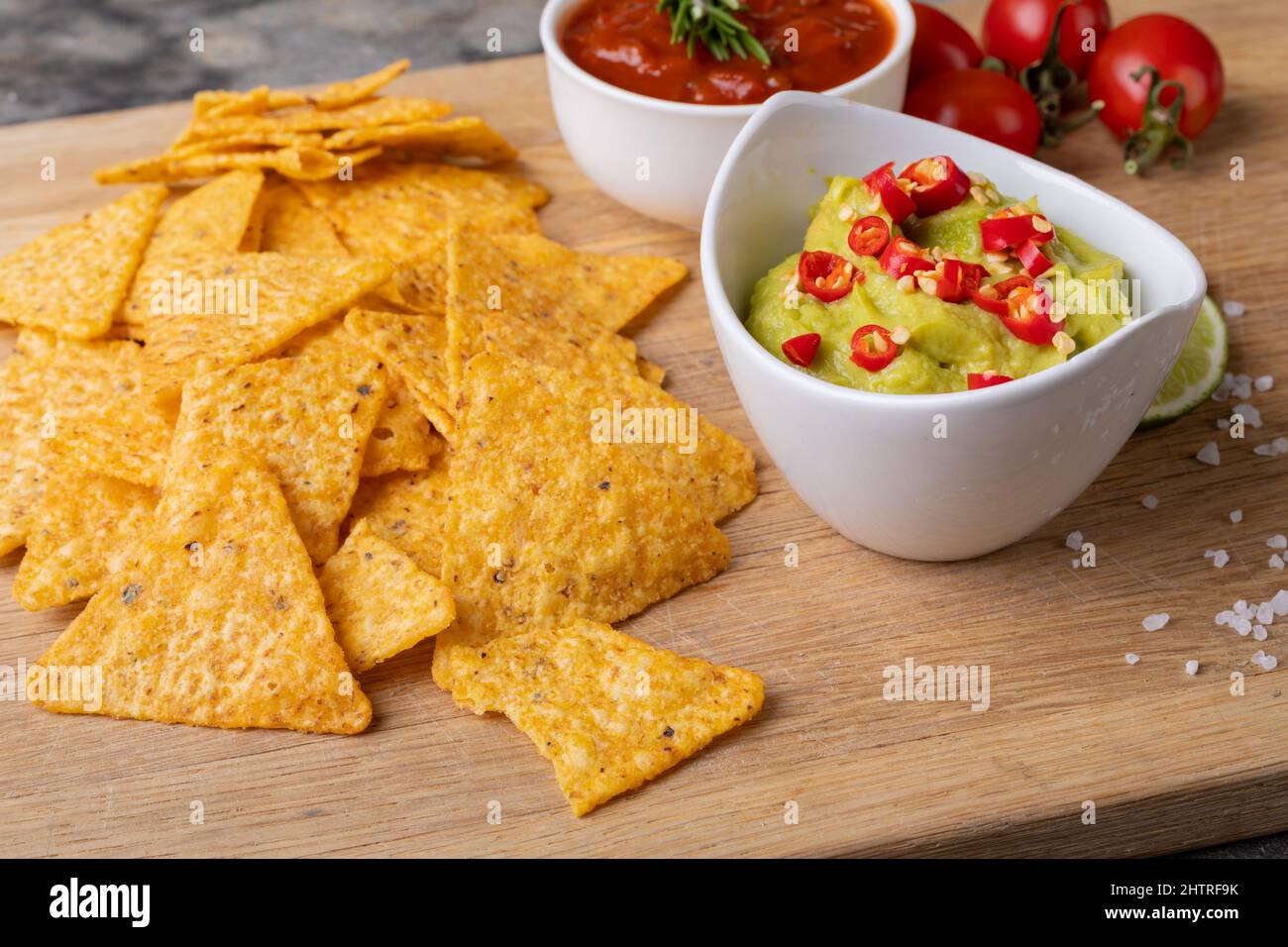 Nahaufnahme von Nacho-Chips mit Saucen und Tomaten auf dem Servierbrett Stockfoto