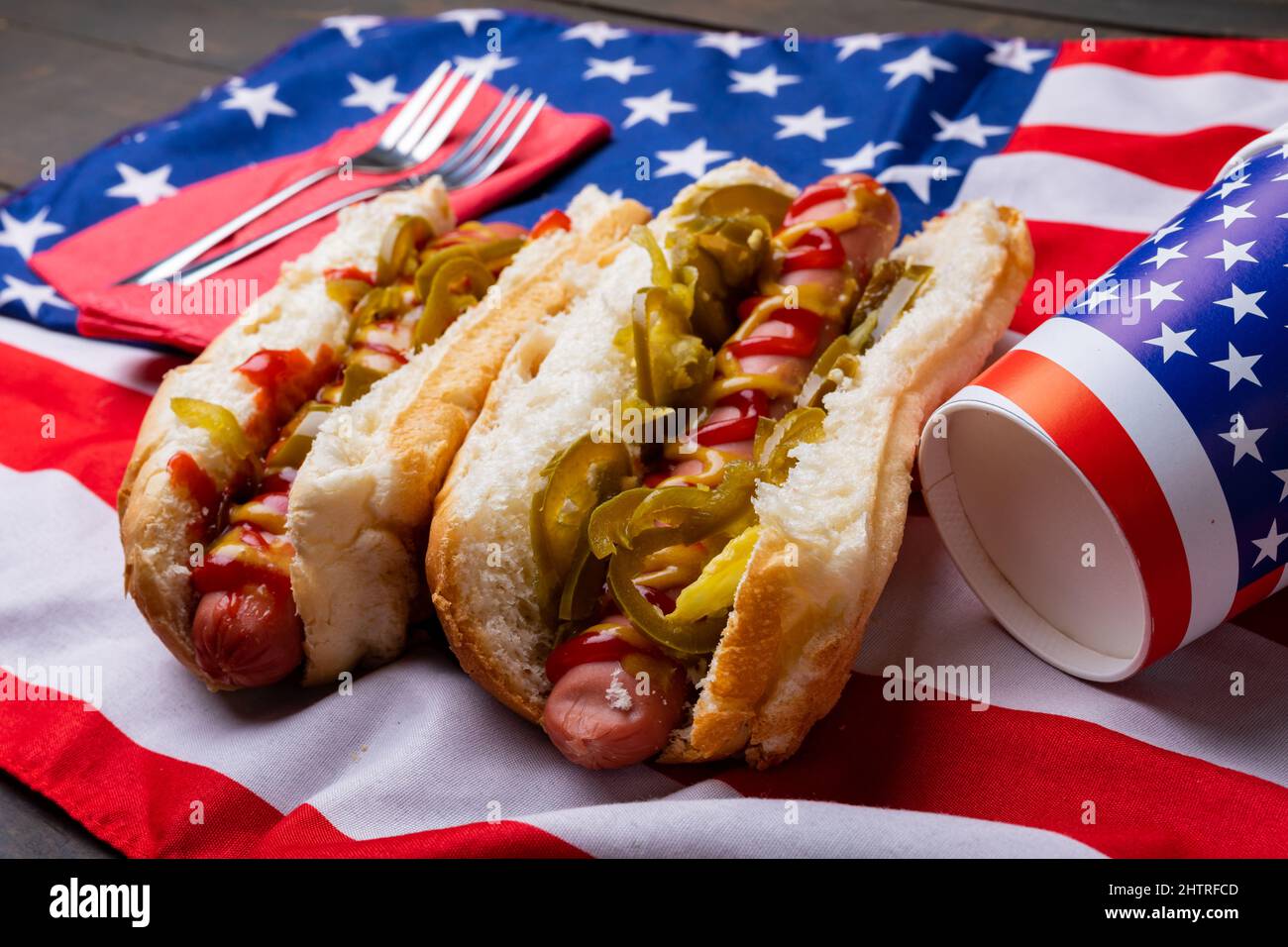 Nahaufnahme von Hot Dogs mit Jalapeno serviert auf amerikanischer Flagge mit Gabel und Einwegbecher Stockfoto
