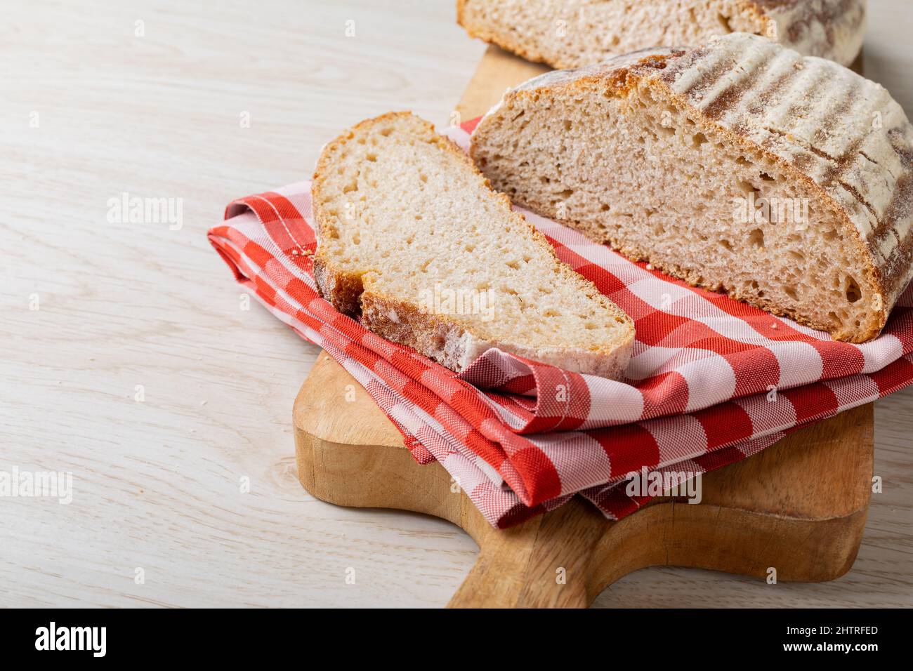 Nahaufnahme von Brot mit karierter Serviette auf dem Servierbrett am Tisch Stockfoto