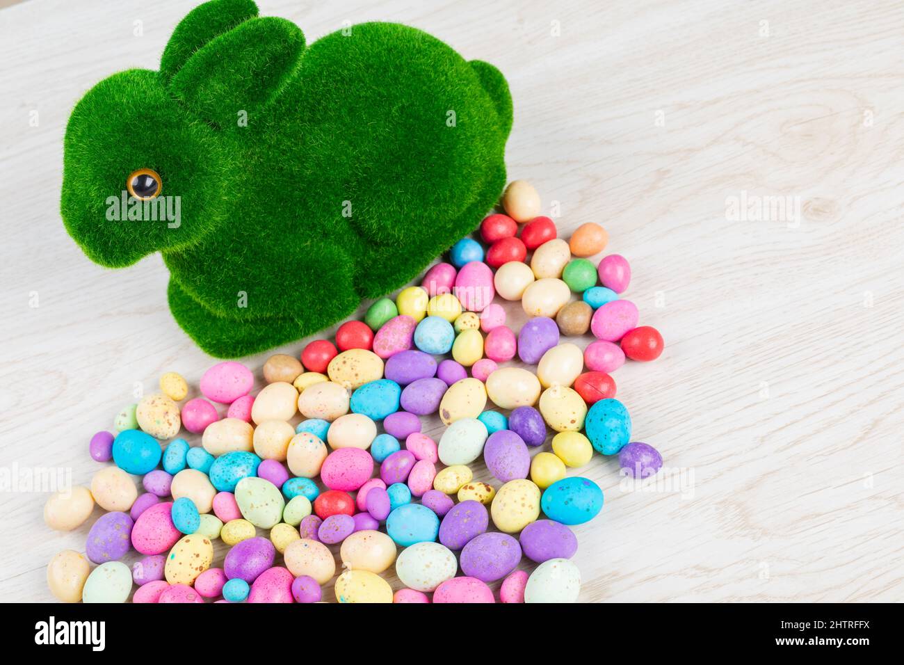 High-Angle-Ansicht von künstlichem Moos Hase mit bunten Süßigkeiten ostereier auf dem Tisch Stockfoto