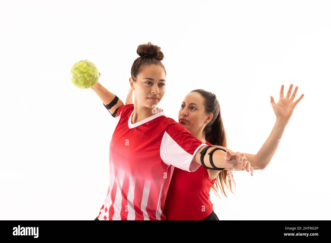 Kaukasische und biraziale junge Handballspielerinnen besiegen vor weißem Hintergrund Stockfoto